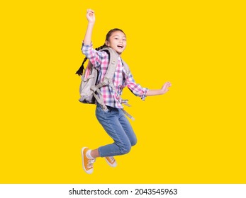 Full length portrait of a happy student girl with bag and jumping.Isolated on yellow background. - Shutterstock ID 2043545963