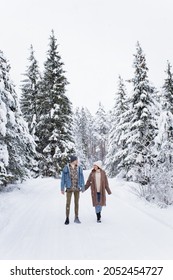 Full Length Portrait Of Happy Young Couple Walking In Winter Forest