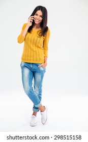 Full Length Portrait Of A Happy Young Woman Talking On The Phone Isolated On A White Background