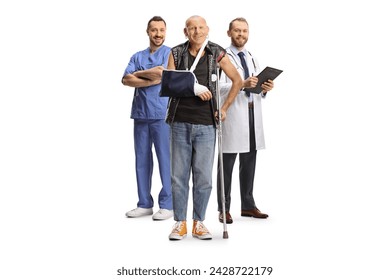 Full length portrait of an injured man with a broken arm and crutch standing with a team of doctors isolated on white background
