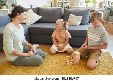 Full Length Portrait Of Loving Family With Special Needs Child Playing Board Games While Sitting On Floor At Home, Copy Space