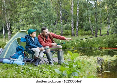 Full length portrait of loving father and son fishing together during camping trip by lake, copy space - Powered by Shutterstock