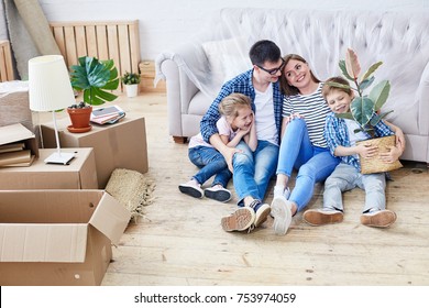 Full Length Portrait Of Loving Young Family Gathered Together In Living Room Of New Apartment And Sharing Ideas Concerning Interior Design, Cute Little Boy Holding Houseplant In Hands