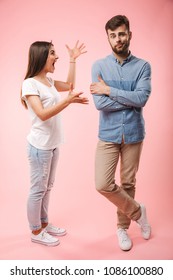 Full Length Portrait Of A Mad Young Couple Having An Argument Isolated Over Pink Background