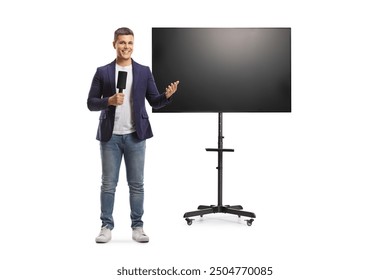 Full length portrait of male presenter holding a microphone and gesturing with hand in front of a tv screen isolated on white background - Powered by Shutterstock