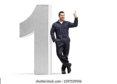 Full Length Portrait Of A Male Worker In An Overall Uniform Leaning On A Big Number One And Pointing Above Isolated On White Background