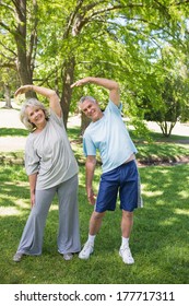 Full length portrait of a mature couple stretching hands at the park