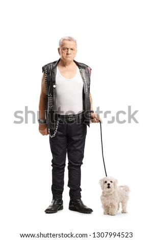 Full length portrait of a mature grumpy punker standing with a maltese poodle dog isolated on white background