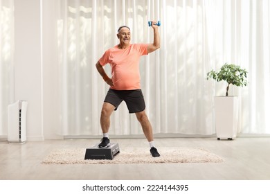 Full length portrait of a mature man exercising step aerobic with a small weight at home - Powered by Shutterstock