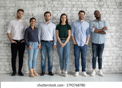 Full Length Portrait Motivated Successful Diverse Employees Team Standing In Modern Office Near Bricks Wall Together, Confident Smiling Business People Colleagues Staff Posing For Corporate Photo