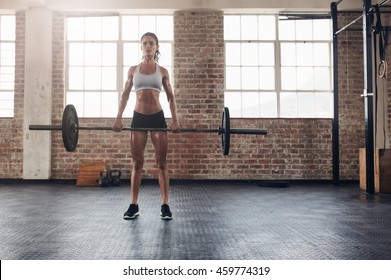 Full Length Portrait Of Muscular Woman In A Gym Doing Heavy Weight Exercises. Fitness Female Doing Weight Lifting At Health Club.