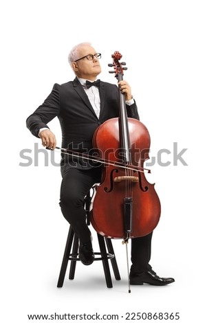 Full length portrait of a musician in a black suit and bow-tie sitting on a chair and playing a cello isolated on white background