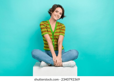 Full length portrait of nice satisfied person sit podium cube toothy smile isolated on turquoise color background - Shutterstock ID 2340792369