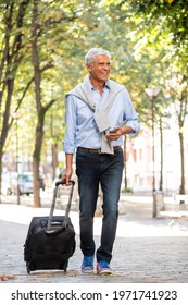 Full Length Portrait Older Man Walking In City With Suitcase And Mobile Phone