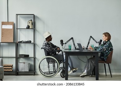 Full length portrait of person in wheelchair giving interview while recording podcast in studio, copy space