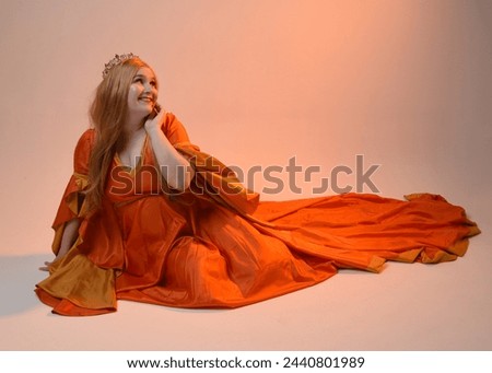Full length portrait of plus size blonde woman, wearing historical medieval fantasy gown, golden crown  royal queen. sitting pose  isolated studio background.