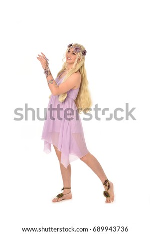 
Full length portrait of a pretty blonde girl  wearing a purple fairy dress. standing pose, isolated against white background.