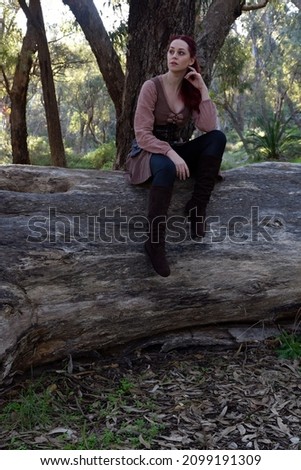 Full length portrait of pretty  female model wearing medieval fantasy adventure costume.  Posing while wondering through a woodland forest background.