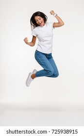 Full length portrait of a pretty joyful woman jumping isolated over white background