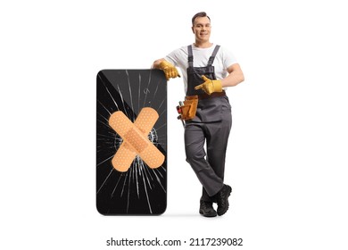 Full length portrait of a repairman leaning on a broken mobile phone with bandage and pointing isolated on white background - Shutterstock ID 2117239082