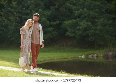 Full length portrait of romantic adult couple embracing while walking towards lake in beautiful nature scenery, copy space - Powered by Shutterstock