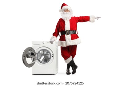 Full length portrait of Santa Claus leaning on a washing machine and pointing to the side isolated on white background   - Powered by Shutterstock