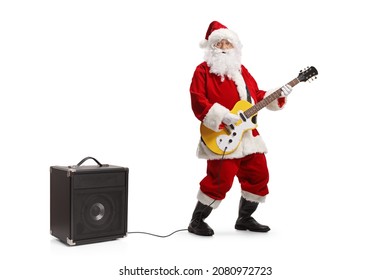 Full length portrait of santa claus playing an electirc guitar plugged into an amplifier isolated on white background - Powered by Shutterstock