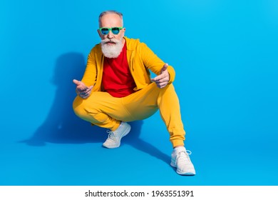 Full length portrait of satisfied aged person squat arms fingers showing isolated on blue color background
