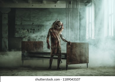 A full length portrait of a scary girl standing near a bed. Halloween. Horror film. - Shutterstock ID 1189043107