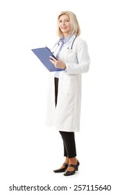 Full Length Portrait Of Senior Female Doctor Holding Clipboard While Standing Against White Background. 