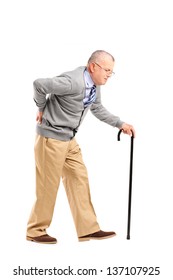 Full length portrait of a senior gentleman walking with cane and suffering from back pain isolated on white background