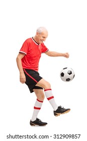 Full Length Portrait Of A Senior Man In A Red Jersey Juggling A Football And Smiling Isolated On White Background