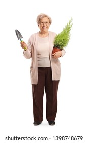 Full Length Portrait Of A Senior Woman Holding A Spade And A Plant Isolated On White Background