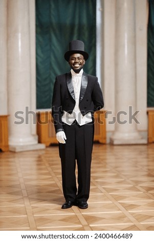 Full length portrait of smiling African American gentleman looking at camera standing in palace hall