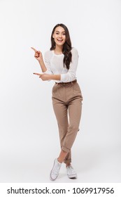 Full Length Portrait Of A Smiling Asian Businesswoman Standing And Pointing Fingers Away Isolated Over White Background