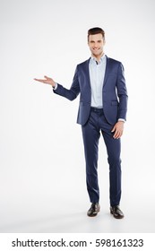 Full Length Portrait Of Smiling Business Man Which Holding Invisible Copyspace On The Pound And Looking At Camera. Isolated White Background