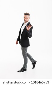 Full length portrait of a smiling mature businessman dressed in suit showing ok gesture isolated over white background - Shutterstock ID 1018465753