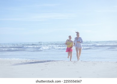 Full length portrait of smiling modern mother and teenage daughter at the beach running. - Shutterstock ID 2255556567