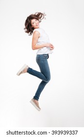 Full length portrait of a smiling pretty woman jumping isolated on a white background