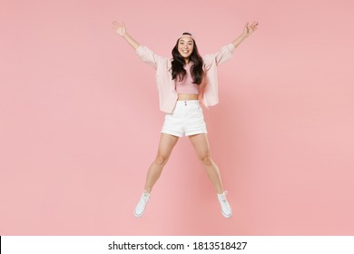 Full length portrait smiling young asian woman in casual clothes, cap isolated on pastel pink background studio portrait. People lifestyle concept. Mock up copy space. Jumping spreading hands and legs - Shutterstock ID 1813518427