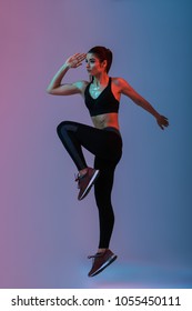 Full Length Portrait Of Sportswoman 20s Wearing Black Tracksuit Practicing In Gym And Doing Workout Isolated Over Neon Lights