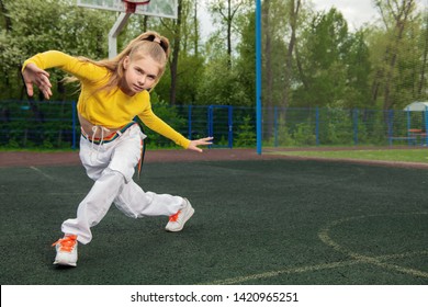 A full length portrait of a sporty teenager girl posing on the sports ground. Sport fashion, active lifestyle.