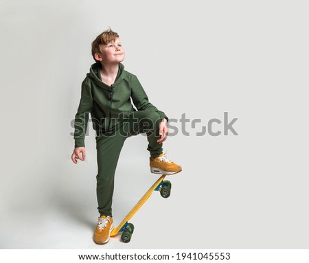 Full length portrait of stylish cute young child boy riding a skateboard isolated against white background. Cool kid skater