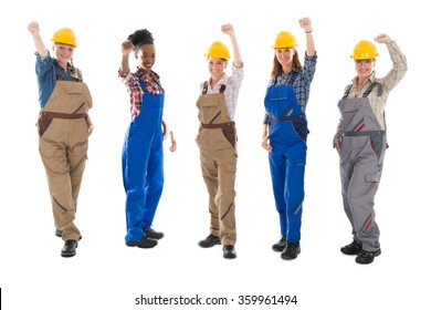 Full length portrait of successful female carpenters with arms raised standing against white background