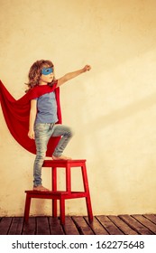 Full Length Portrait Of Superhero Kid Against Grunge Wall Background