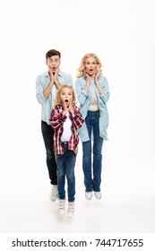 Full Length Portrait Of A Surprised Shocked Family With A Child Jumping With Hands At Face Isolated Over White Background