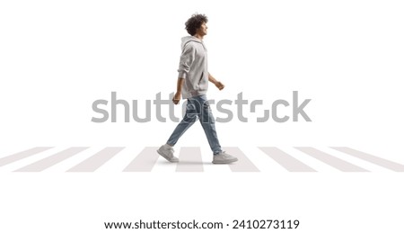 Full length portrait of a tall guy with curly hair walking at a pedestrian crossing isolated on white background
