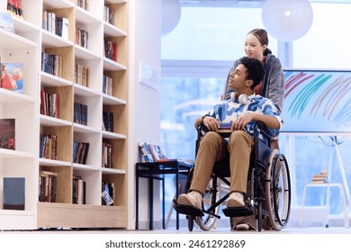 Full length portrait of teenage boy with disability choosing books in school library with smiling girl assisting copy space - Powered by Shutterstock