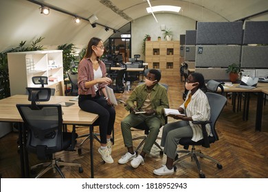 Full Length Portrait Of Three Contemporary Business People Wearing Masks While Discussing Work Project In Modern Office Post Pandemic