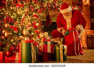 Full Length Portrait Of Traditional Santa Claus Putting Presents Under Christmas Tree, Copy Space